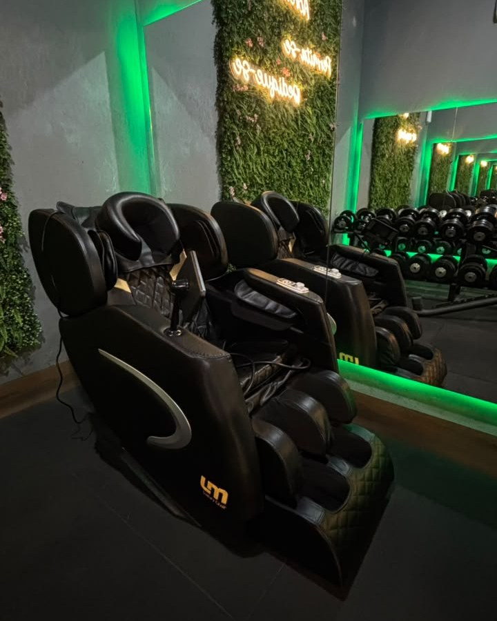 Cadeiras de massagem em frente à parede verde com os neons Acredite, Permita-se e Dedique-se