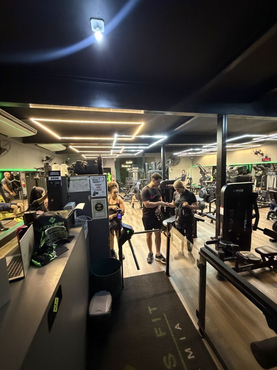 Recepção com catraca e a sala de musculação ao fundo